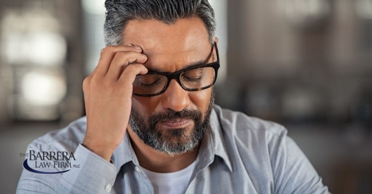Hispanic man with glasses with his hand on his head.