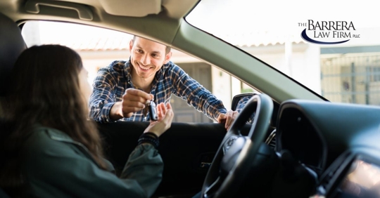 Man giving  keys to a woman driver sitting in a car.