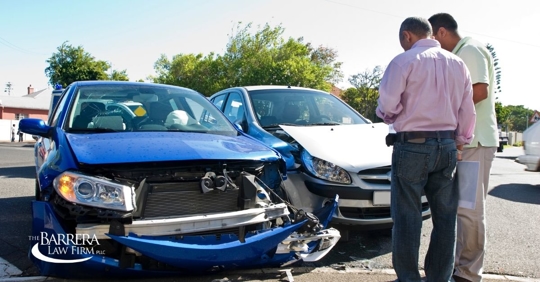 Two men standing in front of their damaged cars after a car accident.